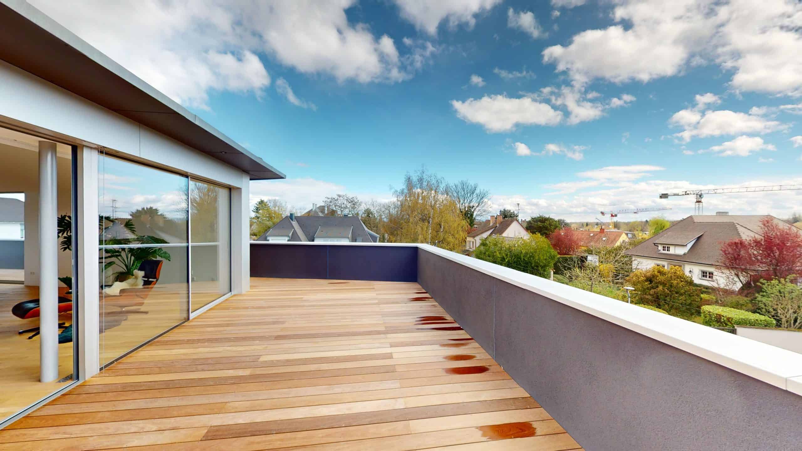 Balcon spacieux avec sol en bois et vue panoramique sur la ville et la nature environnante.
